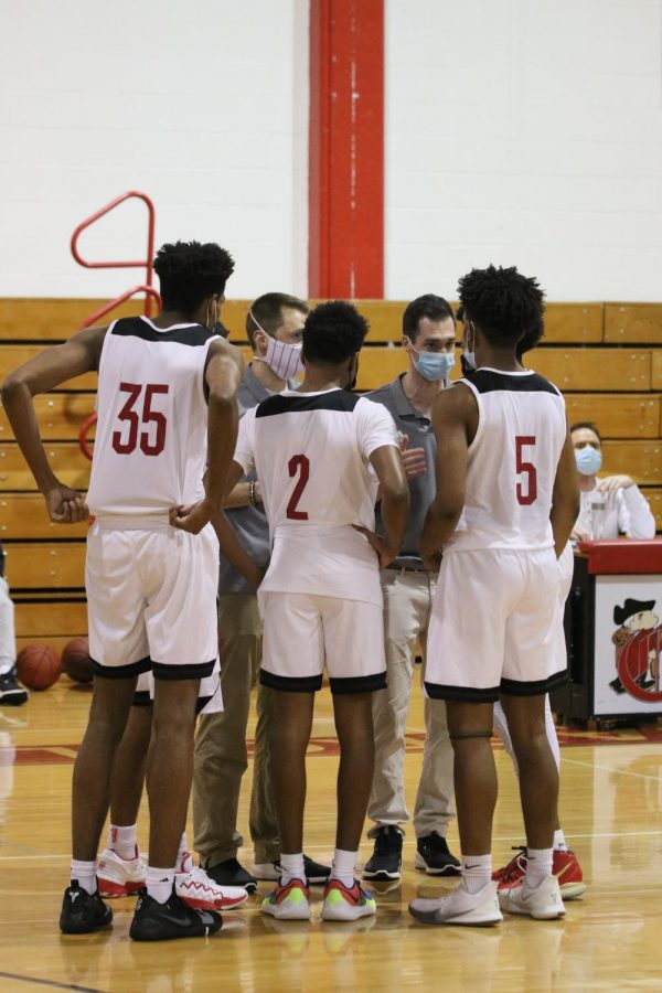 Members of the varsity boys basketball team talk with the coaches during a time out.