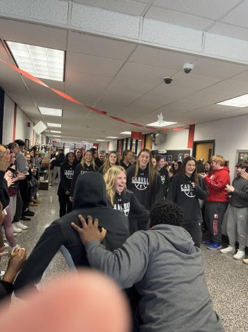 Students cheer the Archbishop Carroll varsity girls basketball team as it makes its way to the bus that will take it to the state championship.