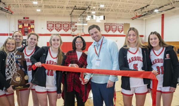 Dr. Tricia Scott, Carrolls president, and Mr. William Gennaro, principal, cut the ribbon for the renovated gym with the help of the girls basketball team.