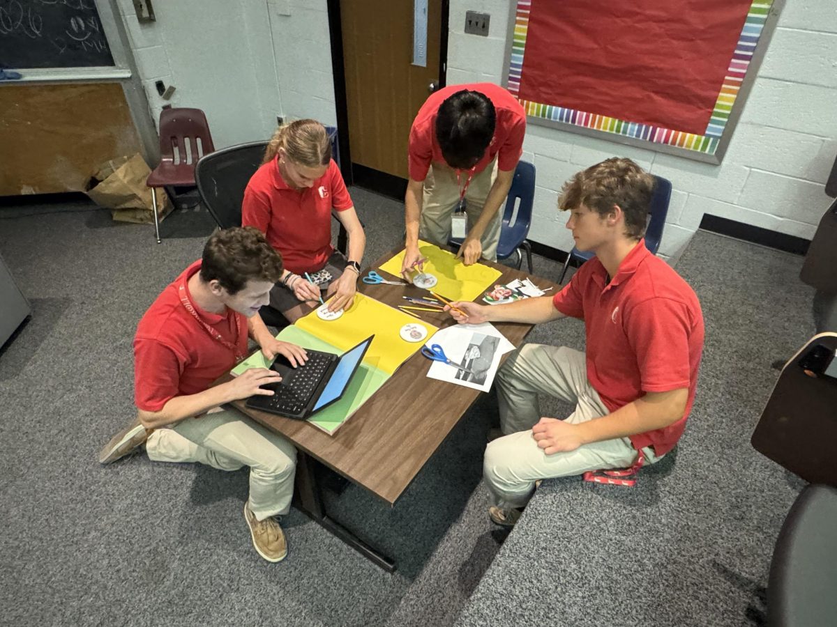 Sophomores Will Wood, Olivia Hermanovich, Connor Hnat, and Francis Durkin work together to create the designs for the senior field day door decorating. 