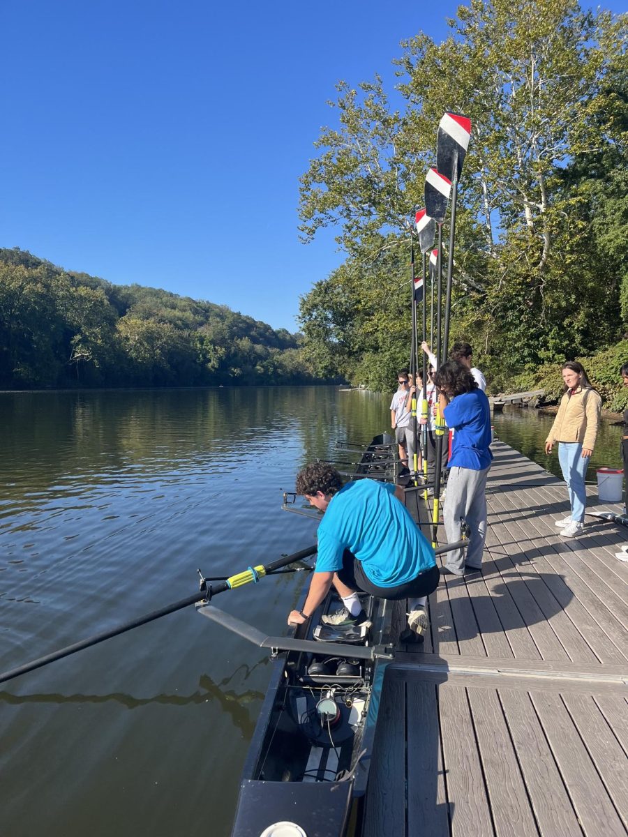 Varsity rower Julian McPherson demonstrates how to correctly place an oar in an oarlock on the boat.